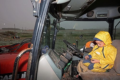 Five-year-old Blake Kowbel watches Lego videos on a phone from the warmth of a tractor cab as his parents work in the field. (Tim Smith/The Brandon Sun)