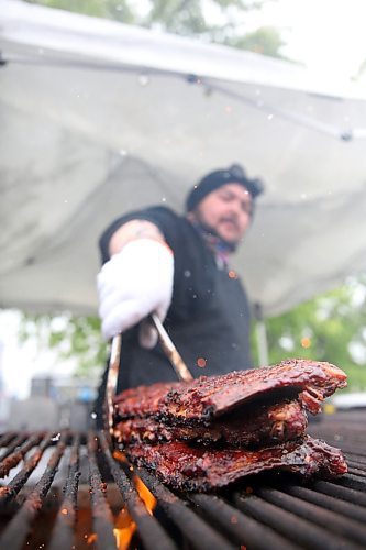 Grill sparks mingle with falling snowflakes as Buckey BBQ griller Brad Bosence stacks racks of ribs on an outdoor grill at the Riverbank Discovery Centre on Friday afternoon. An unseasonal late May snowfall forced the Western Canada Rib Fest Tour to delay opening for several hours. It also prompted  the posteponement of several scheduled entertainment acts to Sunday and the move of Shania Twin's show to The 40 on Friday night. (Matt Goerzen/The Brandon Sun)