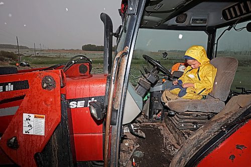 24052024
Five-year-old Blake Kowbel watches Lego videos on a phone from the warmth of a tractor cab as his parents Nathan and Kate Kowbel tie fence for cattle in a field along Highway 10 near their farm north of Brandon during flurries on a wet, snowy and cool Friday. The Kowbel's grow crops in addition to raising cattle and have seeded about 800 acres so far this season but their seeding has been slowed by recent wet weather. 
(Tim Smith/The Brandon Sun)