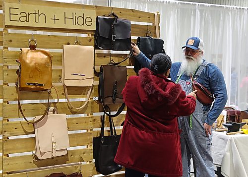 A vendor with Earth and Hide from Winnipeg showcases the leather bags, backpacks and belts to a customer during the Apple and Pine Market held in the Manitoba Room at the Keystone Centre on Saturday. (Michele McDougall/The Brandon Sun)