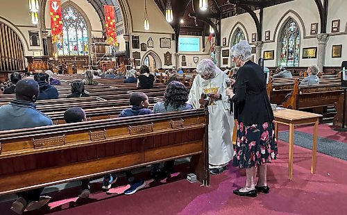 JOHN WOODS / FREE PRESS
Rev. Helen Holbrook bring communion to a mother and her child during a service at Holy Trinity Anglican Church Sunday, May 26, 2024. The church’s foundation is crumbling and the parish is looking for a buyer to help them rebuild it.

