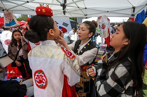 JOHN WOODS / FREE PRESS
Enjoo Jung, director of Red Lotus Korean dance group, puts the finishing touches to Yugyeong Kim, as she gets ready for her performance during Taste of Asia at the Forks Sunday, May 26, 2024. 

Reporter: standup