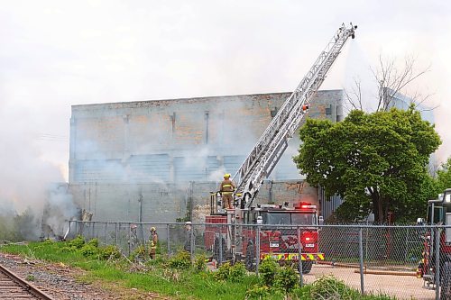 MIKE DEAL / WINNIPEG FREE PRESS
Winnipeg Fire Paramedic Services crews work at putting out a fire as smoke billows from behind a large building at 1010 Logan (Wheelies Roller rink bldng) early Monday morning. 
240527 - Monday, May 27, 2024