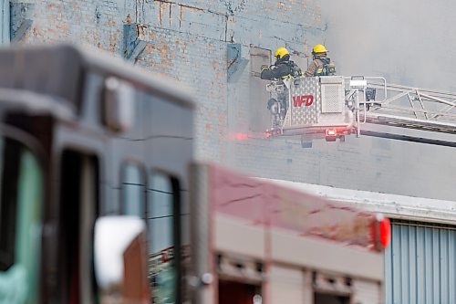 MIKE DEAL / WINNIPEG FREE PRESS
Winnipeg Fire Paramedic Services crews work at putting out a fire as smoke billows from behind a large building at 1010 Logan (Wheelies Roller rink bldng) early Monday morning. 
240527 - Monday, May 27, 2024