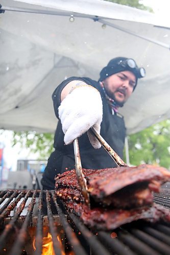 Grill sparks mingle with falling snowflakes as Buckey BBQ griller Brad Bosence stacks racks of ribs on an outdoor grill at the Riverbank Discovery Centre on Friday afternoon. An unseasonal late May snowfall forced the Western Canada Rib Fest Tour to delay opening for several hours. It also prompted  the posteponement of several scheduled entertainment acts to Sunday and the move of Shania Twin's show to The 40 on Friday night. (Matt Goerzen/The Brandon Sun)