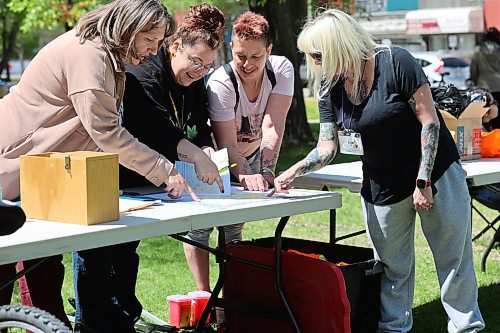 The City of Brandon's Amanda Dupuis and Shannon Saltarelli (from left) with Community Housing and Wellness, share a laugh with Katrina Salmon from Brandon's Manitoba Harm Reduction Network, and Sonia McCormich with Ask Auntie while looking at the map for the downtown spring clean-up. (Michele McDougall/The Brandon Sun)