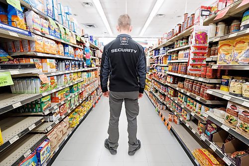 MIKE DEAL / FREE PRESS ILLUSTRATION 
An Impact Security guard walks down a grocery isle.
240531 - Friday, May 31, 2024.