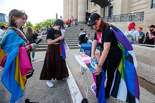 JOHN WOODS / FREE PRESS
Shauna Fay irons flags for Liv Daivdson, left, Cali and anyone that needs little pressing as they attend Pride parade in Winnipeg Sunday, June 2, 2024. 

Reporter: tyler