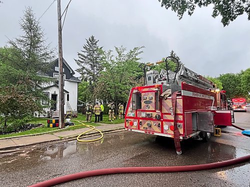 A fire truck and other emergency vehicles block access to the 300 block of 16th Street while firefighters attempt to douse a house fire on Tuesday morning. (Matt Goerzen/The Brandon Sun)