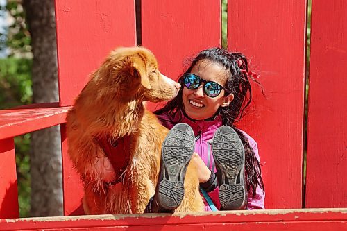 06062024
Parisa Jiwa sits in an oversized Adirondack chair with her dog Ender while visiting Wasagaming in Riding Mountain National Park from Calgary with family on Thursday. 
(Tim Smith/The Brandon Sun)