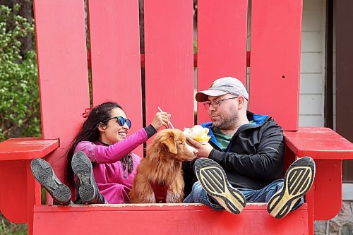 06062024
Parisa Jiwa and Keegan Hill-Mann enjoy a sundae together in an oversized Adirondack chair with their dog Ender while visiting Wasagaming in Riding Mountain National Park from Calgary with family on Thursday. 
(Tim Smith/The Brandon Sun)