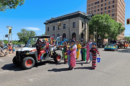 Some clowns and jokers stop to give a wave on Rosser Avenue during the annual Travellers' Parade. (Charlotte McConkey/The Brandon Sun)