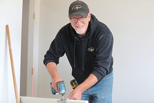 Carpenter Barry Ewasiuk installs hinges on one of the bedroom doors. (Michele McDougall/The Brandon Sun)