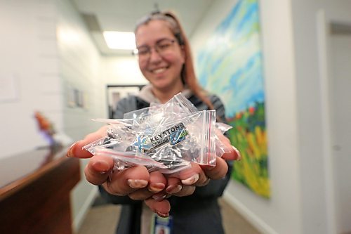 A smiling Cassie Martens, the ticketing and marketing coordinator for the Keystone Centre in Brandon, holds out a large handful of pins on Wednesday that celebrate the 50th anniversary of the facility. (Matt Goerzen/The Brandon Sun)