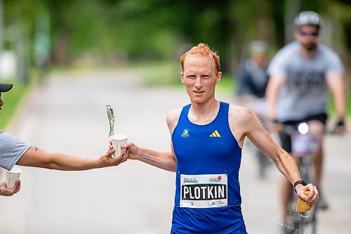 BROOK JONES / FREE PRESS
David Plotkin (right) grabs a cup of water from Manitoba Marathon volunteer Vern Dalusong as he runs down Wellington Crescent while competing in the men's full marathon, which was the 46th running of the Manitoba Marathon in Winnipeg, Man., Sunday, June 16, 2024.