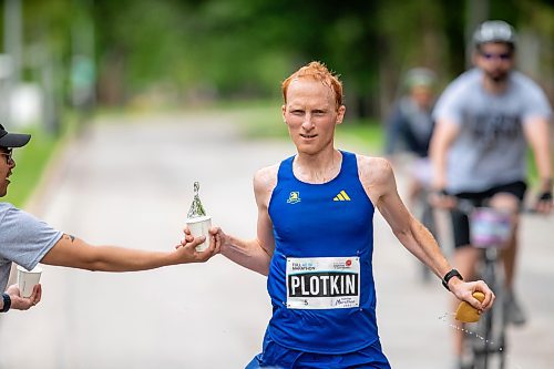 BROOK JONES / FREE PRESS
David Plotkin (right) grabs a cup of water from Manitoba Marathon volunteer Vern Dalusong as he runs down Wellington Crescent while competing in the men's full marathon, which was the 46th running of the Manitoba Marathon in Winnipeg, Man., Sunday, June 16, 2024.