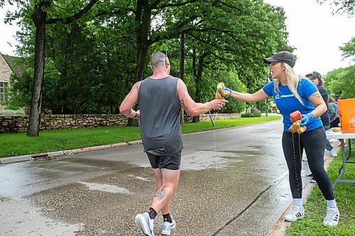 BROOK JONES / FREE PRESS
Manitoba Marathon volunteer Kristen Friess (right) hands out water-soaked sponge to full marathon runners at a fluids station along Wellington Crescent during the 46th running of the Manitoba Marathon in Winnipeg, Man., Sunday, June 16, 2024.