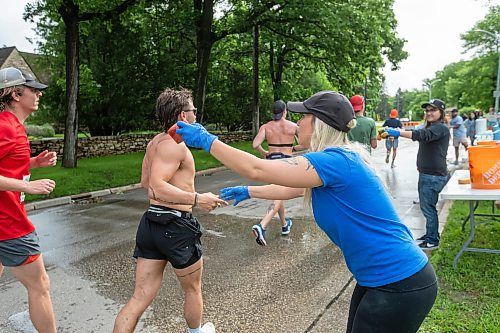 BROOK JONES / FREE PRESS
Manitoba Marathon volunteer Kristen Friess (right) hands out water-soaked sponge to full marathon runners at a fluids station along Wellington Crescent during the 46th running of the Manitoba Marathon in Winnipeg, Man., Sunday, June 16, 2024.