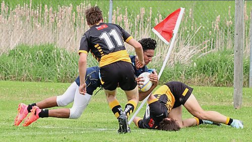 Miguel Dominguez of the Brandon Barbarians dives through a pair of Wasps to touch the ball down for a try during a Rugby Manitoba Division 2 league game at John Reilly Field last weekend. The Barbs have roared out to a 3-0 start. (Photos by Perry Bergson/The Brandon Sun)