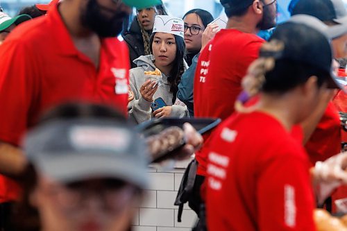 MIKE DEAL / FREE PRESS
Juri Rogers eats a free donut while waiting in line.
Lovers of fried pastries endured long lines and rainy conditions to be some of the first to purchase Krispy Kreme donuts during it&#x2019;s grand opening early Tuesday.
240618 - Tuesday, June 18, 2024.