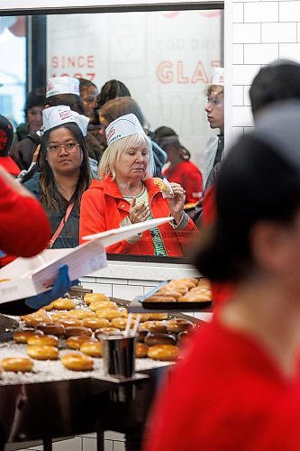 MIKE DEAL / FREE PRESS
Debra Gyde eats a free donut while waiting in line.
Lovers of fried pastries endured long lines and rainy conditions to be some of the first to purchase Krispy Kreme donuts during it&#x2019;s grand opening early Tuesday.
240618 - Tuesday, June 18, 2024.