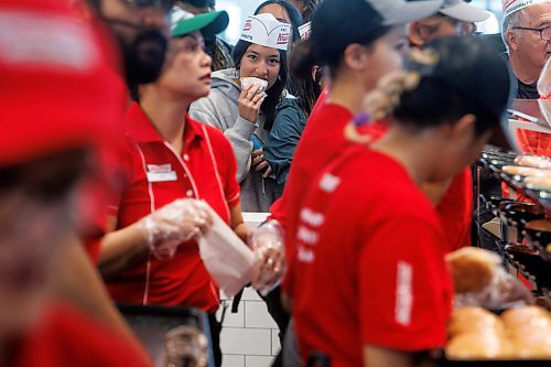 MIKE DEAL / FREE PRESS
Juri Rogers eats a free donut while waiting in line.
Lovers of fried pastries endured long lines and rainy conditions to be some of the first to purchase Krispy Kreme donuts during it&#x2019;s grand opening early Tuesday.
240618 - Tuesday, June 18, 2024.