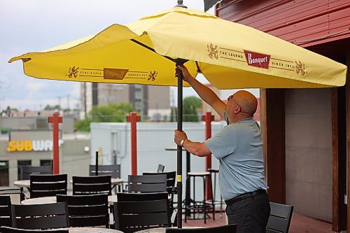 Georgie’s Lounge general manager Guy Lobreau sets the umbrella at the spot's rooftop patio on Friday, ready for the weekend. (Abiola Odutola/The Brandon Sun)