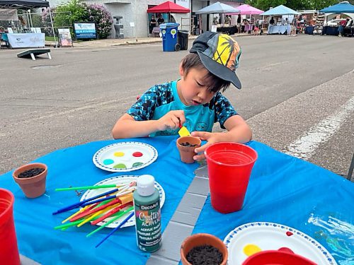 Desean Heudebourck paints a flower pot at the Big Brothers Big Sisters of Westman booth during Saturday's “Kickin off Summer” downtown Brandon block party, a collaboration between The Dock on Princess, Section 6 Brewing Co., Kickin’ Axe., and Brandon Downtown BIZ. (Michele McDougall/The Brandon Sun) 
