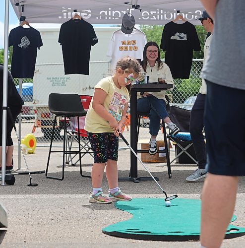 Naveah Calvert tries her hand at the putting challenge during Saturday's “Kickin off Summer” downtown Brandon block party, a collaboration between The Dock on Princess, Section 6 Brewing Co., Kickin’ Axe., and Brandon Downtown BIZ. (Michele McDougall/The Brandon Sun) 