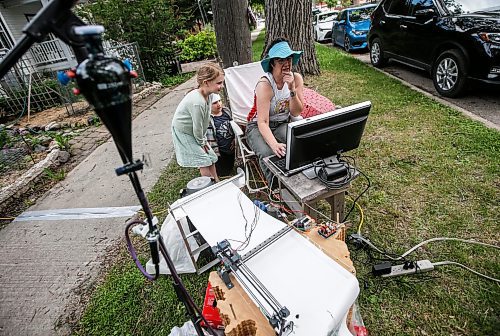 JOHN WOODS / FREE PRESS
Ellianna, Theo and their father Dave stopped by to visit media artist Erika Jean Lincoln as she works on her Winnipeg project Arboreal Intuitions - an urban tree memorial on Clifton Street in Winnipeg Sunday, June 23, 2024. Lincoln&#x2019;s project uses a computer drawing plotter with gravity fed ink to draw digital images of the ring patterns from the stumps of Winnipeg&#x2019;s harvested trees.

Reporter: ?