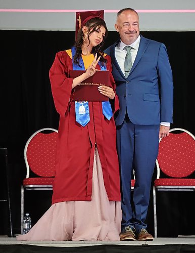 Graduate Mercedes Demas flashes a peace sign while posing for photos with principal Bryce Ridgen after receiving her diploma on Monday. (Tim Smith/The Brandon Sun)