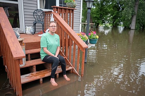 Rachel Morsching sits Tuesday, June 25, 2024, on the flooded porch of her father Dean Roemhildt's home in Waterville., Minn. Waters from the nearby Tetonka and Sakatah lakes have encroached on the town amid recent heavy rains. (Casey Ek/The Free Press via AP)