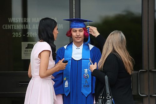 Prairie Hope School graduate Xavier Myran's grandmother Dianne Berchaluk adjusts his cap and tassle while his girlfriend Kiyanne Monkman stands with them prior to his graduation ceremony at the Western Manitoba Centennial Auditorium on Thursday afternoon. (Matt Goerzen/The Brandon Sun)