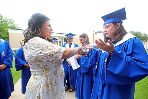 Prairie Hope High School student Ashley Happyjack Pompana washes herself in smoke during an Indigenous smudging ceremony conducted by Indigenous Academic Support Cheyanne Seaton, outside the Western Manitoba Centennial Auditorium on Thursday afternoon prior to the graduation ceremony. (Matt Goerzen/The Brandon Sun)