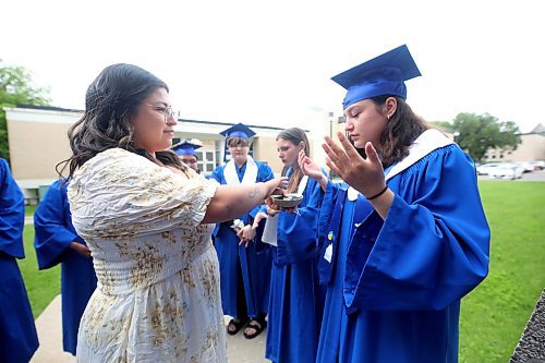 Prairie Hope High School student Ashley Happyjack Pompana washes herself in smoke during an Indigenous smudging ceremony conducted by Indigenous Academic Support Cheyanne Seaton, outside the Western Manitoba Centennial Auditorium on Thursday afternoon prior to the graduation ceremony. (Matt Goerzen/The Brandon Sun)