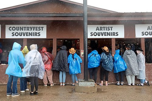 Festivalgoers wear ponchos during pouring rain as they check out merchandise for sale. (Tim Smith/The Brandon Sun)