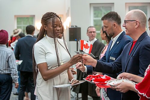 BROOK JONES / FREE PRESS
A CanadIan citizenship ceremony was hosted on Canada Day at the Pavilion at Assiniboine Park in Winnipeg, Man., Monday, July 1, 2024. Pictured: Oreo Amogu, 31, (left) receives a Canadian flag from Winnipeg Mayor Scott Gillingham after she took the oath of citizenship. Amogu and her husband Henry Amogu immigrated from Nigeria to Canada. Henry also took the oath of citizenship.