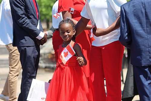 The daughter of Steve Dada from Nigeria admires the Canadian flag she was given after becoming a citizen during a ceremony at the International Peace Garden on Canada Day. (Charlotte McConkey/The Brandon Sun)