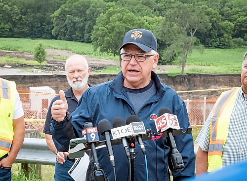 Minnesota Gov. Tim Walz addresses media members Tuesday, July 2, 2024, at the Rapidan Dam, in Rapidan, Minn. Rushing waters from the Blue Earth River have already left a trail of debris and destruction on the edges of a southern Minnesota dam that partially failed last week. (Casey Ek/The Free Press via AP)