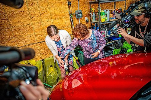 NIC ADAM / FREE PRESS
Electric vehicle owner Shelley Kowalchuck (centre right) shows Environment and Climate Change Minister Tracy Schmidt (centre left) and press how to pulg in her car in her home on Tuesday.
240702 - Tuesday, July 02, 2024.

Reporter: Martin Cash