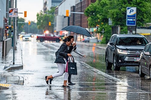 NIC ADAM / FREE PRESS
Two women cross at the corner of Smith Street and Graham Avenue on a rainy Thursday afternoon.
240704 - Thursday, July 04, 2024.

Reporter: