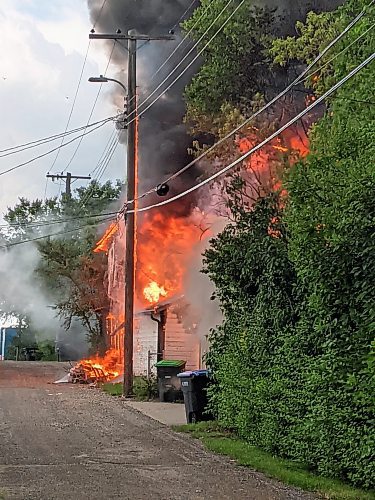 Flames engulf one of the garages and a hydro pole. Power was temporarily cut to the area as the hydro wire posed a safety risk to responding firefighters. There were no reported injuries. (Geena Mortfield/The Brandon Sun)