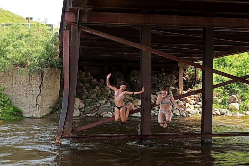 Leighton Calcut and Bailey Anderson leap from girders under the Daly-Whitehead Centennial Bridge while swimming in the Little Saskatchewan River on a hot Monday afternoon. (Tim Smith/The Brandon Sun)