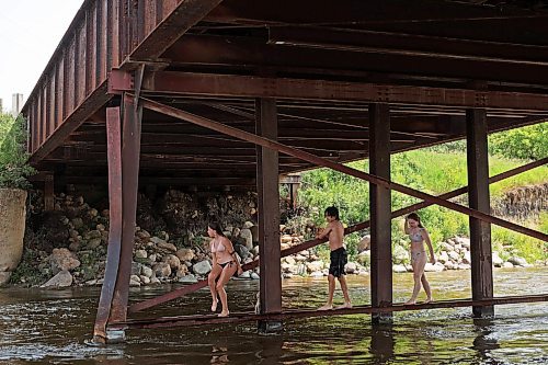 08072024
Siblings Leighton Calcut, Cale Calcut and Bailey Anderson climb on girders under the Daly - Whitehead Centennial Bridge while swimming in the Little Saskatchewan River on a hot Monday afternoon. 
(Tim Smith/The Brandon Sun)