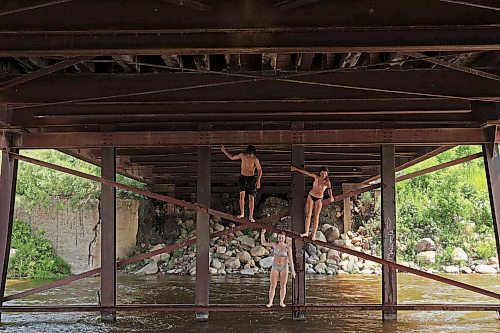 08072024
Siblings Cale Calcut, Bailey Anderson and Leighton Calcut climb on girders under the Daly - Whitehead Centennial Bridge while swimming in the Little Saskatchewan River on a hot Monday afternoon. 
(Tim Smith/The Brandon Sun)