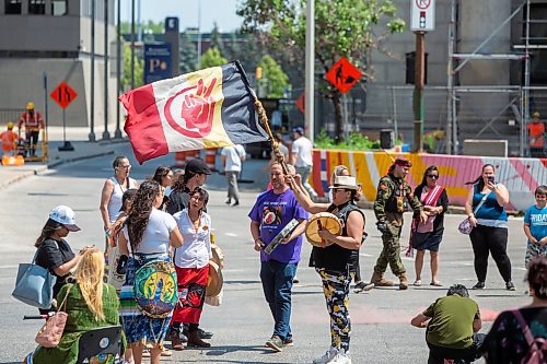 BROOK JONES / FREE PRESS
A woman holds an American Indian Movement flag and an aboriginal drum during a round dance at the intersection of Portage Avenue and Main Street in Winnipeg, Man., on the afternoon of Thursday, July 11, 2024. The round dance was organized following the announcement that a judge ruled serial killer Jeremy Anthony Michael Skibicki is criminally responsible for slaying four indigenous women in Winnipeg in early 2022.