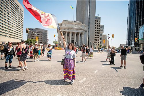 BROOK JONES / FREE PRESS
Winnipeg resident Jessica Courchene, who is from Sagkeeng First Nation, is pictured holding an American Indian Movement flag following a round dance at the intersection of Portage Avenue and Main Street in Winnipeg, Man., on the afternoon of Thursday, July 11, 2024. The round dance was organized following the announcement that a judge ruled serial killer Jeremy Anthony Michael Skibicki is criminally responsible for slaying four indigenous women in Winnipeg in early 2022.