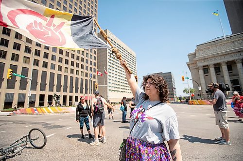 BROOK JONES / FREE PRESS
Winnipeg resident Jessica Courchene, who is from Sagkeeng First Nation, is pictured holding an American Indian Movement flag following a round dance at the intersection of Portage Avenue and Main Street in Winnipeg, Man., on the afternoon of Thursday, July 11, 2024. The round dance was organized following the announcement that a judge ruled serial killer Jeremy Anthony Michael Skibicki is criminally responsible for slaying four indigenous women in Winnipeg in early 2022.