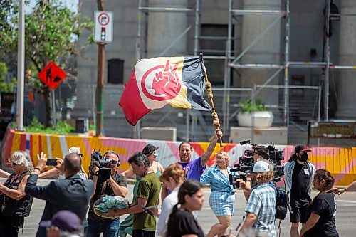 BROOK JONES / FREE PRESS
Travis Brasy holds an American Indian Movement flag during a round dance at the intersection of Portage Avenue and Main Street in Winnipeg, Man., on the afternoon of Thursday, July 11, 2024. The round dance was organized following the announcement that a judge ruled serial killer Jeremy Anthony Michael Skibicki is criminally responsible for slaying four indigenous women in Winnipeg in early 2022.