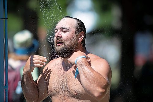 BROOK JONES / FREE PRESS
Folk Fest goer Carl Hiebert, 28, who is from Winnipeg, Man., keeps cool by taking advantage of the public shower at a cooling station at the 49th Winnipeg Folk Festival at Birds Hill Provincial Park in Man., Sunday, July 14, 2024. Hiebert has been attending Folk Fest since 2013.